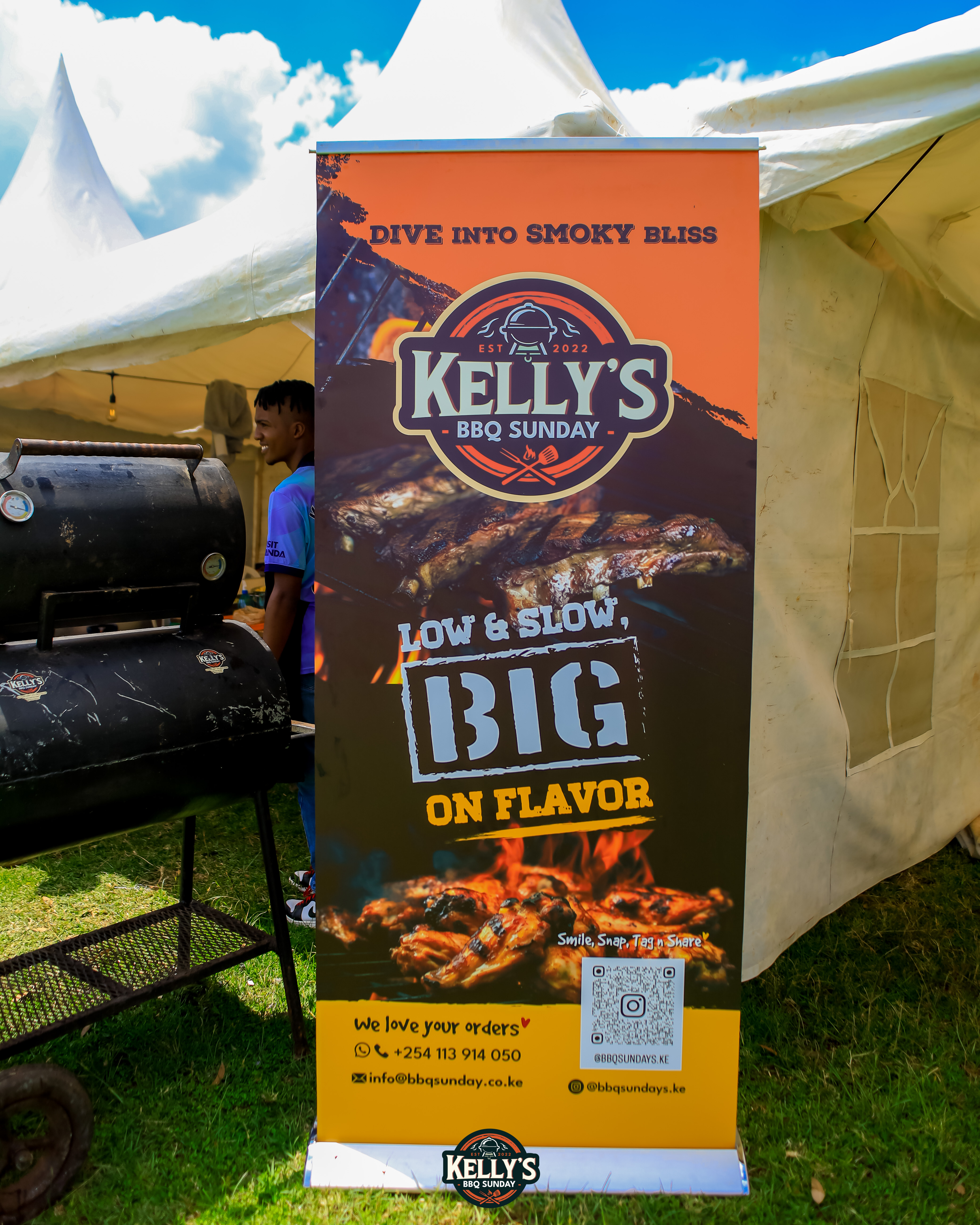 Kelly's BBQ Sunday 'Low and Slow, Big on Flavor' brand banner at an outdoor event in Nairobi
