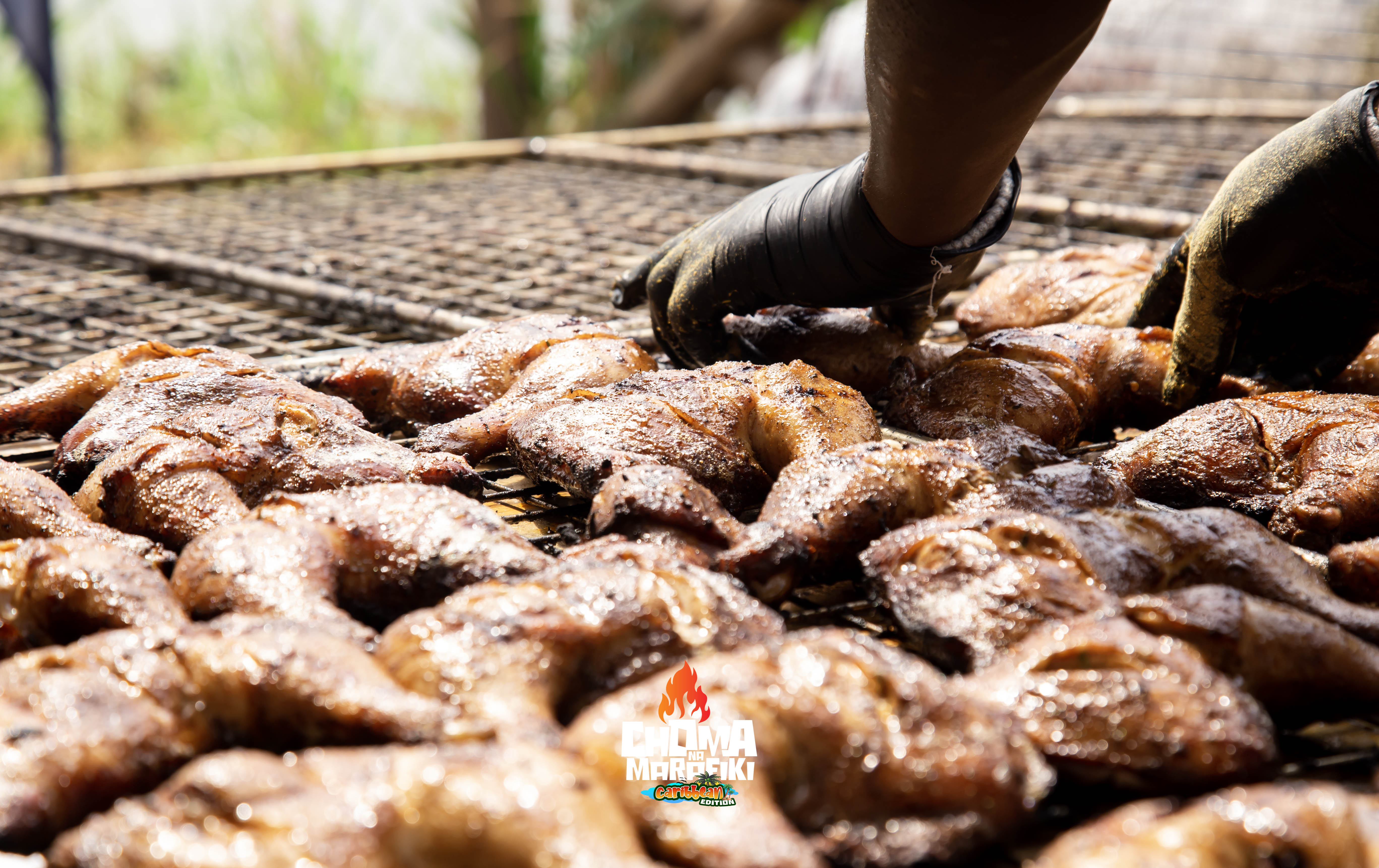 Grillmaster basting whole fish with spice marinade on large grill
