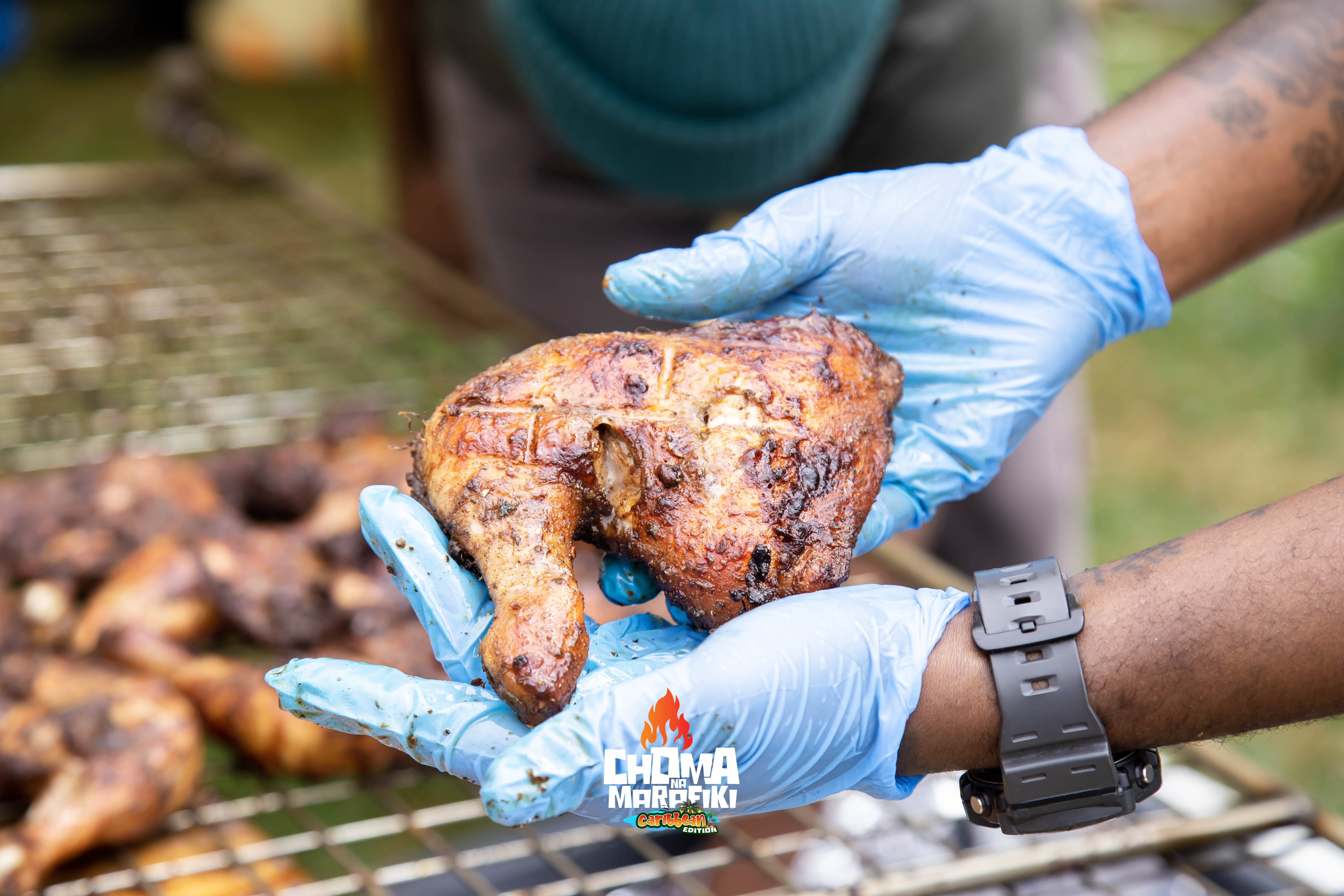 Marinated chicken cooking on rack over roaring fire at Caribbean Edition