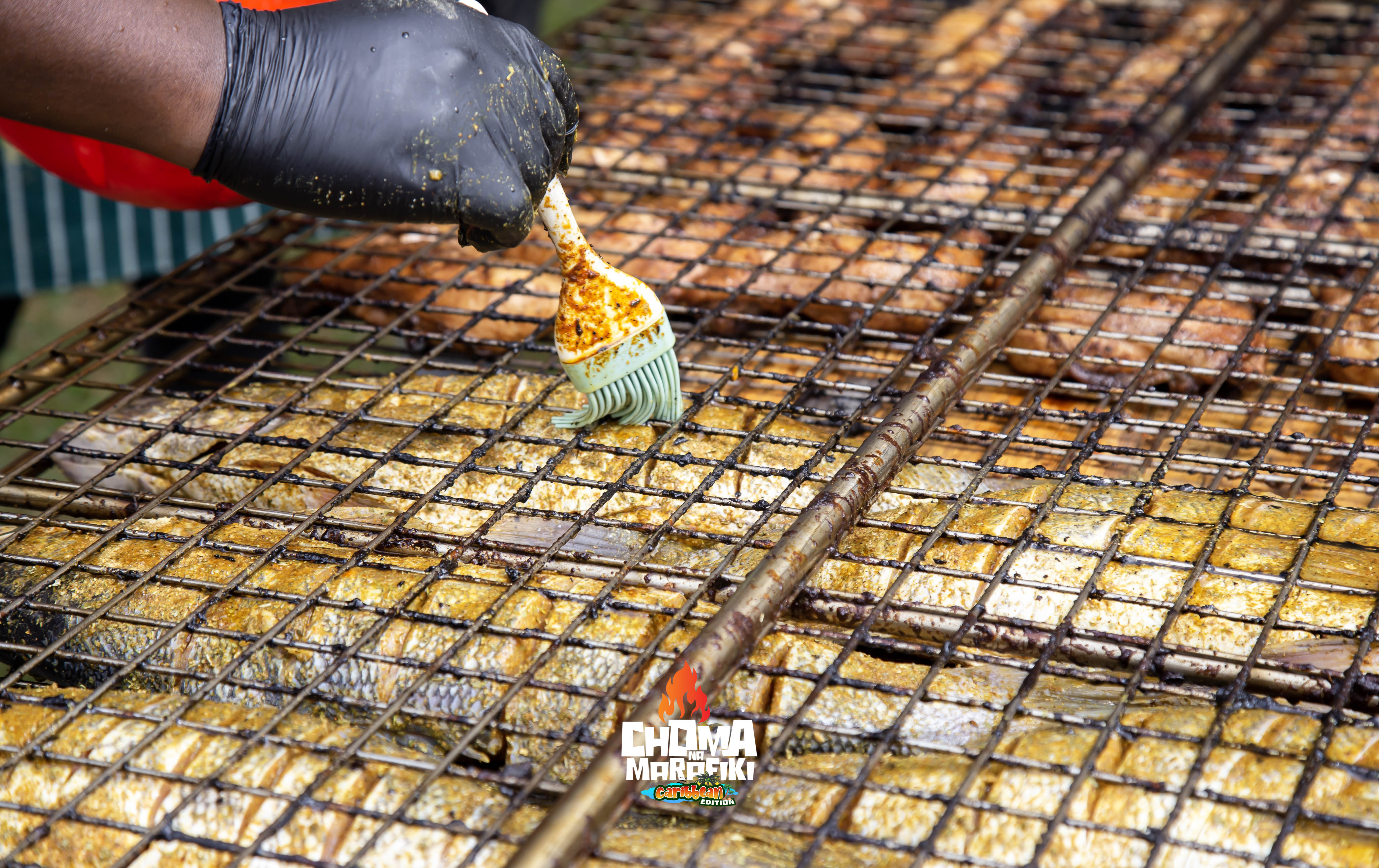 Smoked jerk chicken pieces cooking over open flames at Caribbean Edition